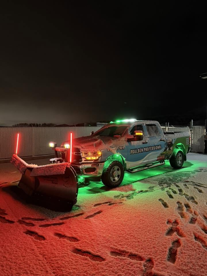 Snow plow truck clearing a Pocatello driveway at night